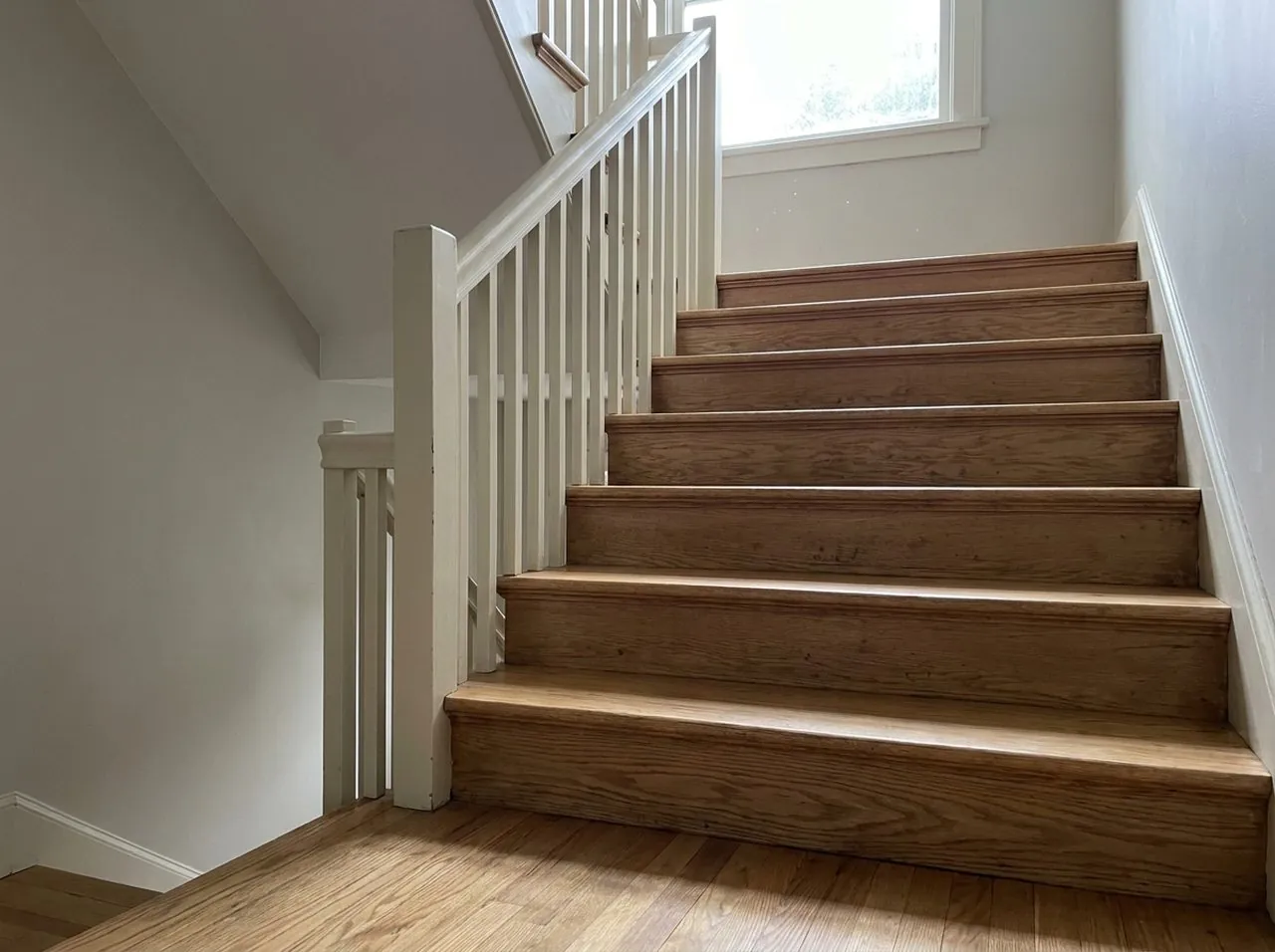 Refinished oak stair treads and risers rising from a matching hardwood floor